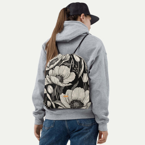 Turnbeutel mit schwarz-weißem Blütendesign wird über der Schulter getragen.